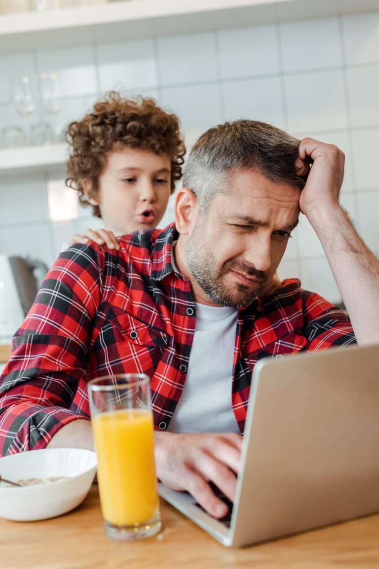 Frustrated worker at home with son by his side