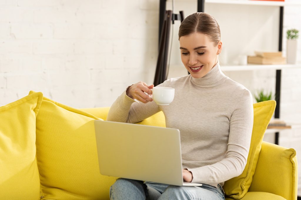 Professional woman having a cup of tea during virtual meeting