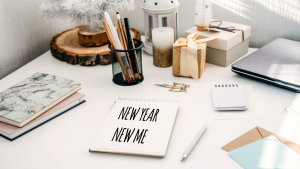 A desk with a notebook that has the text new year new me